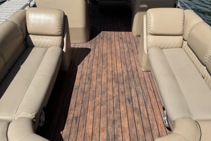 View of a boat's seating area with beige seats and wooden deck.