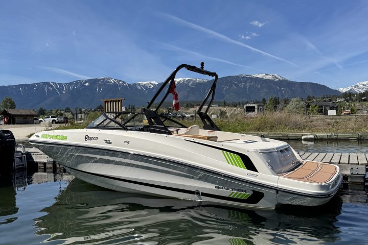Speedboat docked on a calm lake with snowy mountains in the background.
