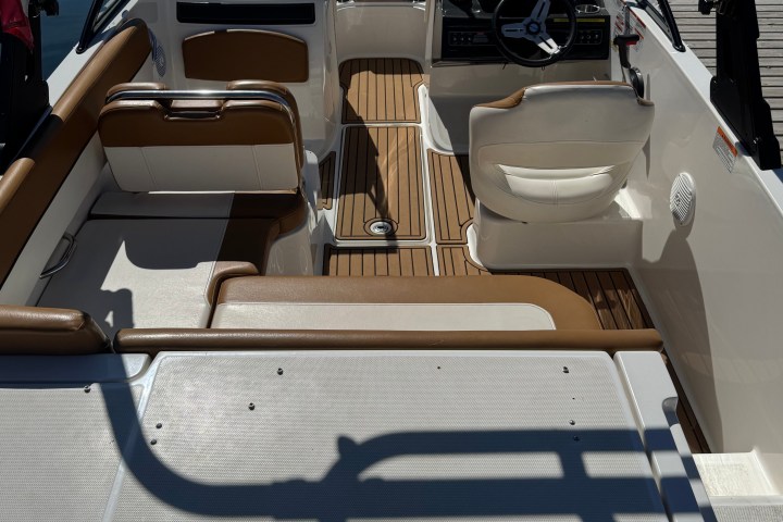 Interior of a docked motorboat with seats and steering wheel.