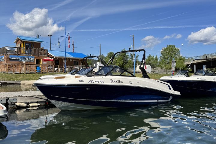 Boat docked by a wooden building on a sunny day with blue sky and clouds.