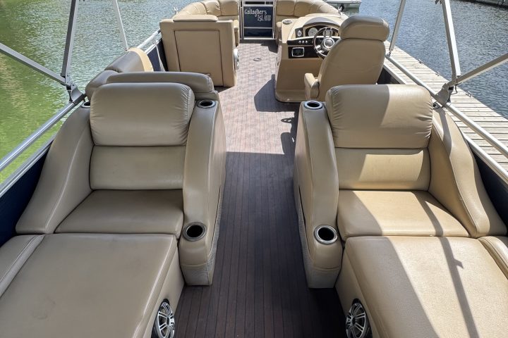 Interior of a boat with beige seating along a canal.
