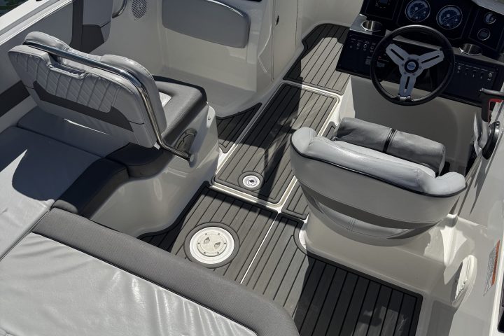Interior of a boat with grey seats and a steering wheel view.