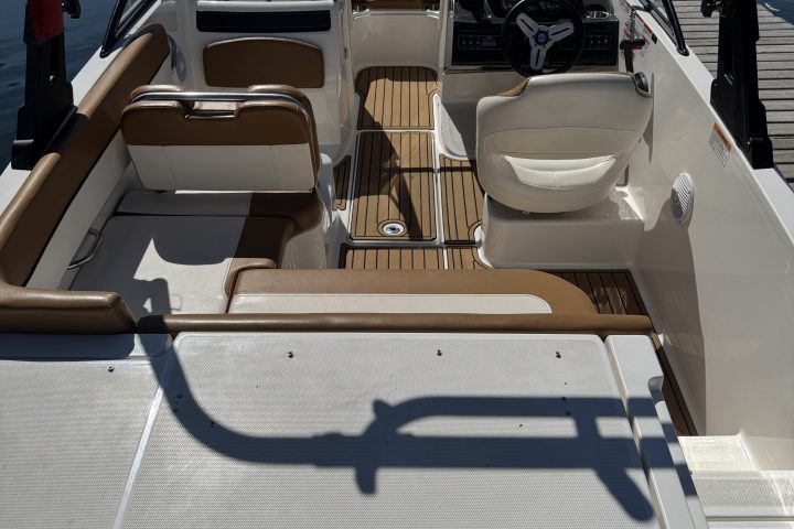 Interior of a small boat with white and brown seating at a dock.