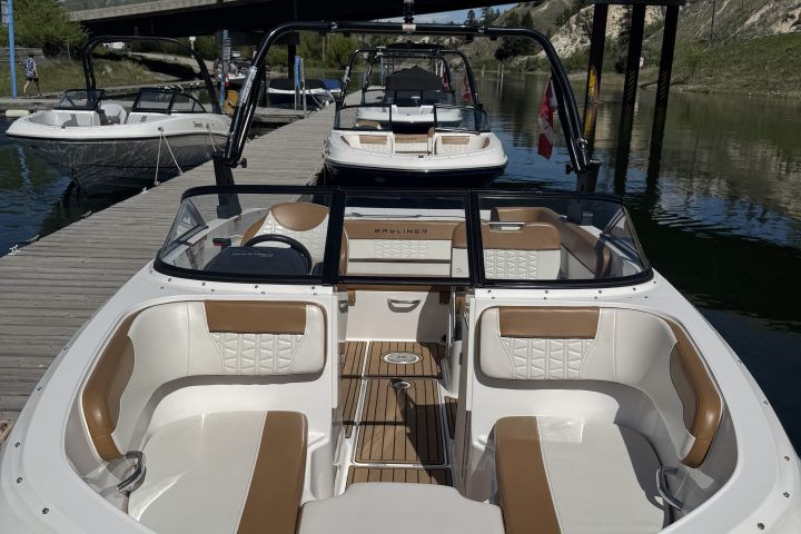 White and brown motorboat docked next to a wooden pier under a bridge.