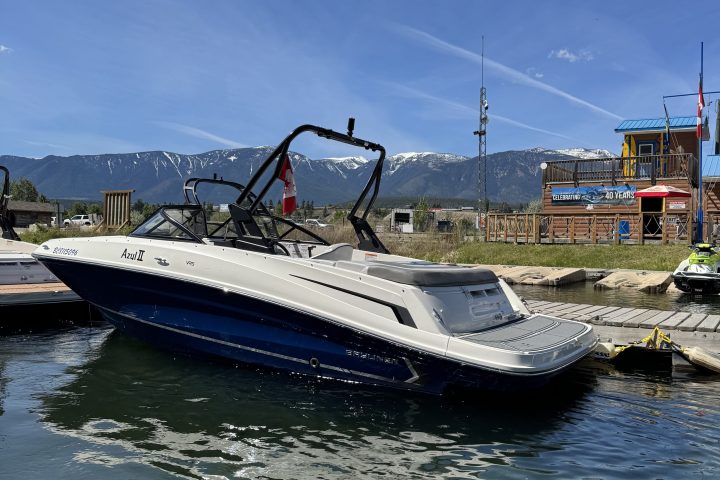 Motorboat docked on a lake with mountains in the background.