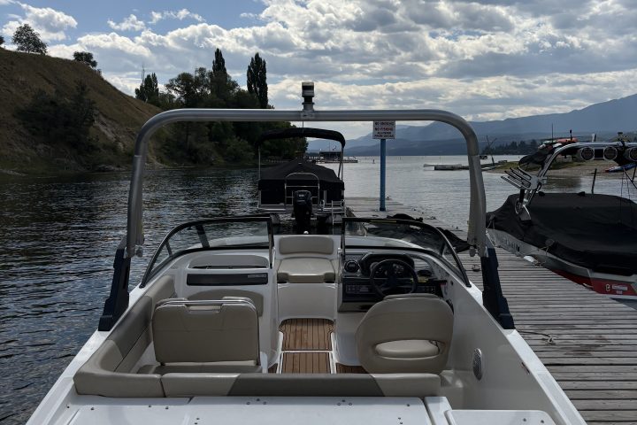 Small white boat docked, with cloudy sky and water view.