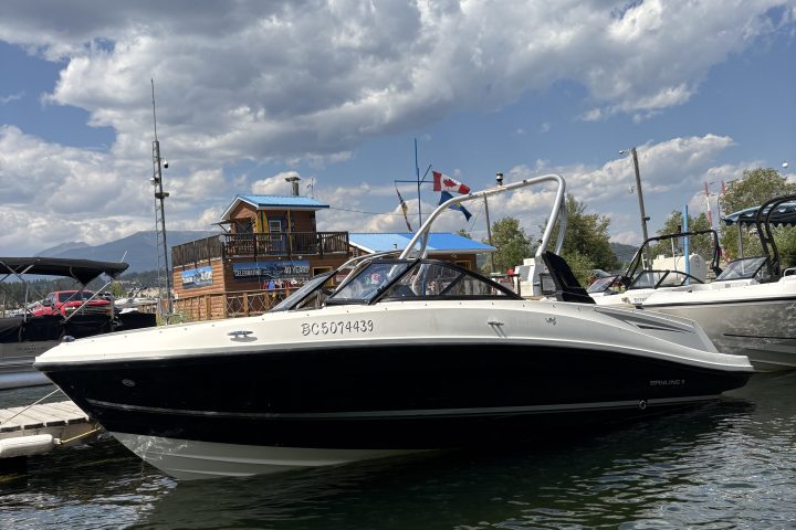 Boat docked at a harbor with cloudy sky and building in the background.