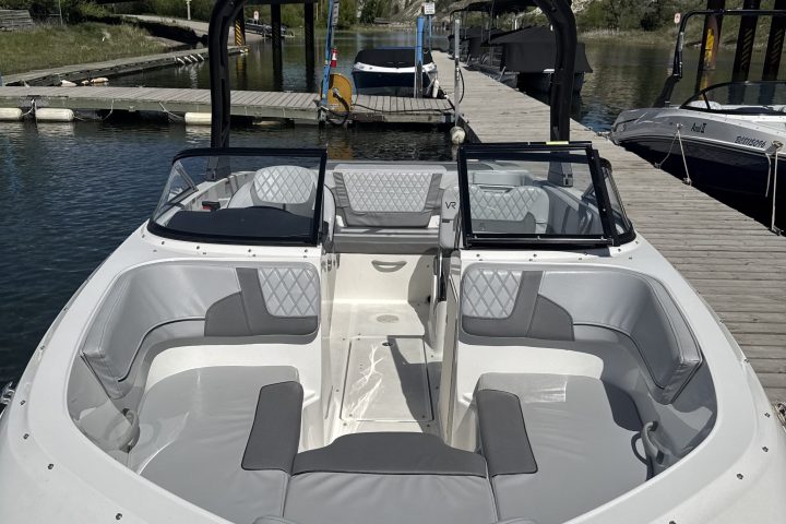 White motorboat docked near a bridge with a clear blue sky.